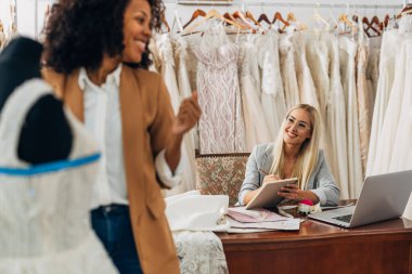 İki kadın bir gelinlik salonunda birlikte çalışıyor..