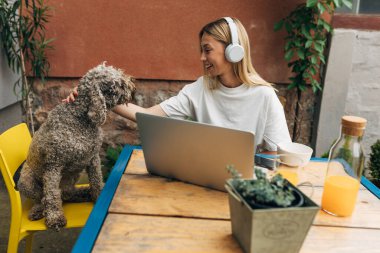 Güzel bir genç kadın ve köpeği bir sandalyeye oturup sarılıyorlar.