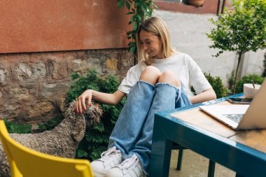 Genç ve tatlı bir kadın bir köpeği okşuyor..