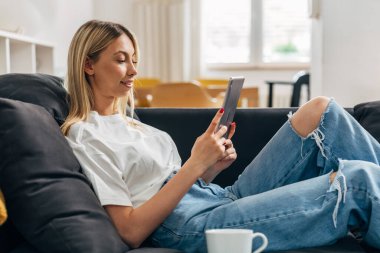 Evinde tablet kullanan güzel bir genç kadının profil görüntüsü.