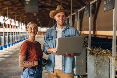 Genç erkek ve kadın portresi dizüstü bilgisayarla ahırda..