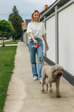 Sarışın, beyaz bir kadın mahallesinde köpekle konuşuyor..