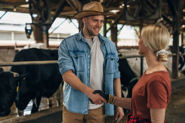 stock image A man with a leghorn is shaking hands with a blond woman with gloves working in a stall.