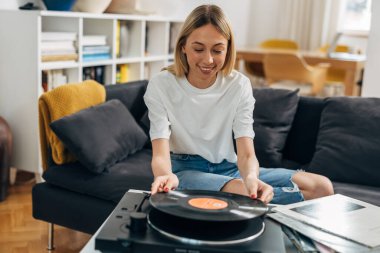 Mutlu genç bir kadın plak plaklarından müzik çalıyor..