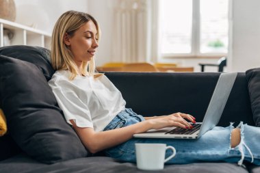 Laptopla çalışan beyaz bir kadının yan görüntüsü.