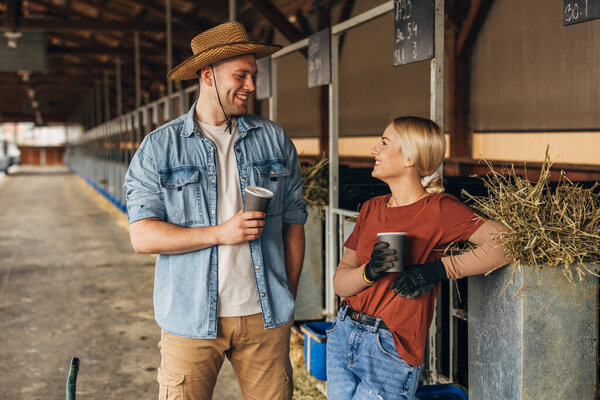 Two farmers enjoying a coffee break together in a stable.