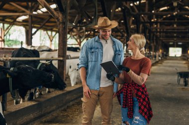 Ahırda dijital tabletle çalışan iki kişi..