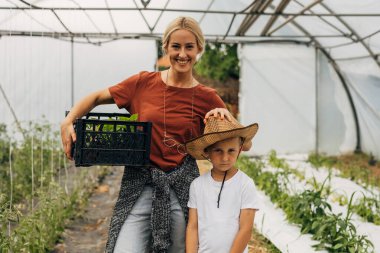 Mutlu anne ve ciddi çocuk bir serada birlikte çalışıyorlar..