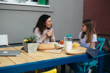 Anne ve kızı arka bahçede birlikte kahvaltı ediyorlar..