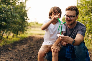 Baba oğluyla yel değirmeni oyuncağı kullanarak oynuyor..
