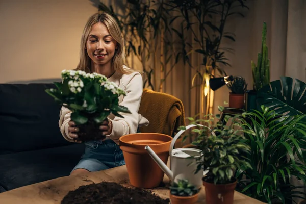 stock image A beautiful blond woman enjoys taking care of her houseplants.