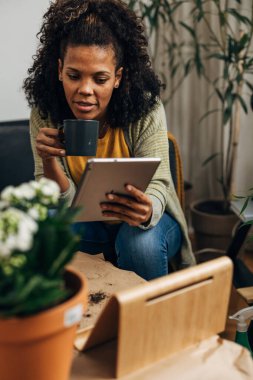 Tablette haber okuyan ve kahve içen çok ırklı bir kadın..