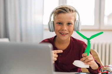Yel değirmeni modelini gösteren mutlu bir çocuğun ön görüntüsü..