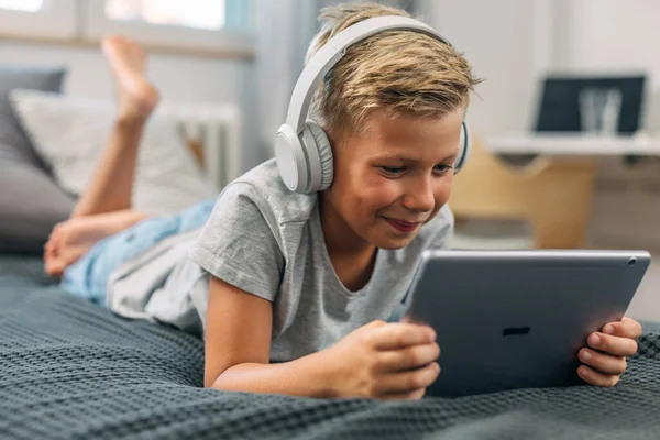 Junge Liegt Mit Tablet Und Kopfhörer Auf Dem Bett — Stockfoto