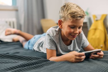 Çocuk yatakta cep telefonu kullanıyor..