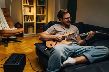 Beyaz adam evde elektro gitar çalıyor..