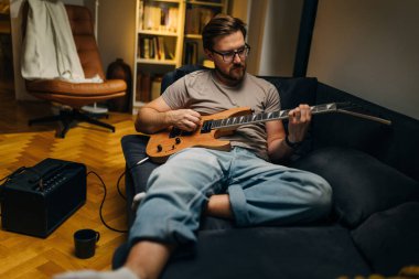 Evde gitar çalma pratiği yapan müzisyen..