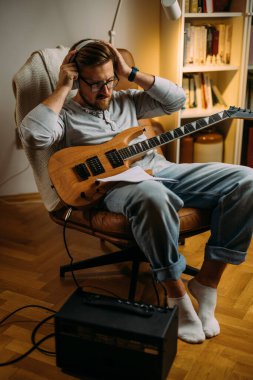 Müzisyen elektro gitar çalmadan önce kulaklık takar..