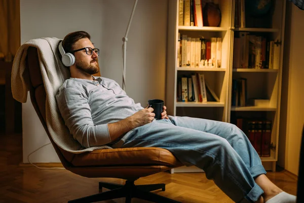 Caucasian man with eyes closed enjoying music with headphones while relaxing at home