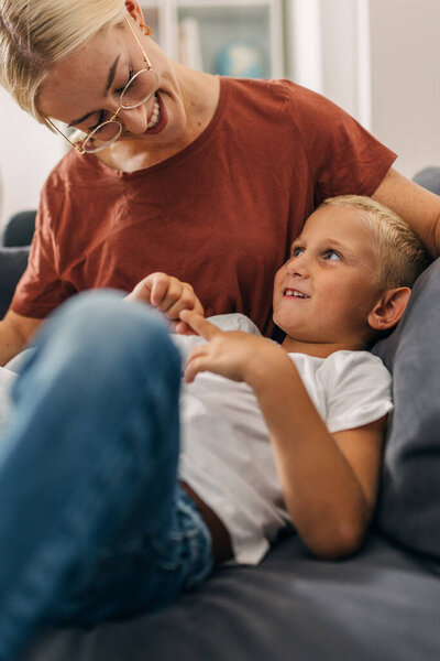 Мать и сын сидят на диване и разговаривают.