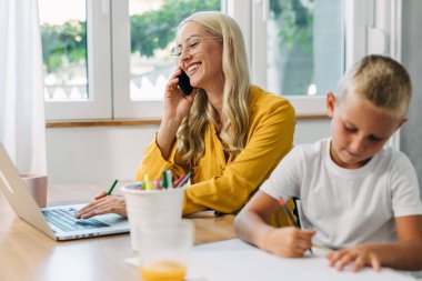 Oğlu yanında resim çizerken annesi telefonda konuşuyor..