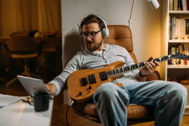 Rahat adam evde gitar çalıyor..