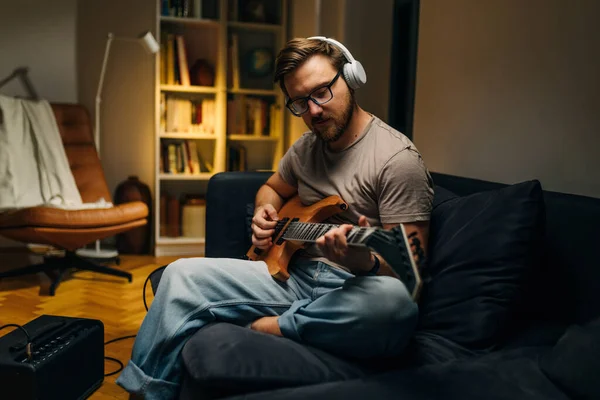 Musician is practicing guitar in home studio.