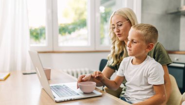 Laptopta film izleyen anne ve oğulun yan görüntüsü.