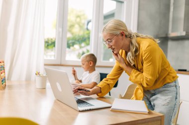 Güzel genç anne oğluyla ilgilenirken evden çalışıyor..