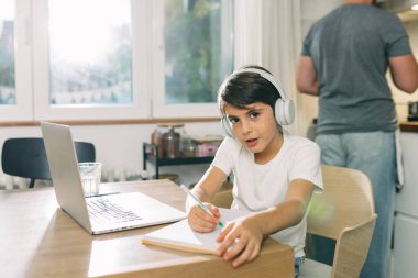 Beyaz çocuk ödevini yapıyor ve dizüstü bilgisayar kullanıyor..