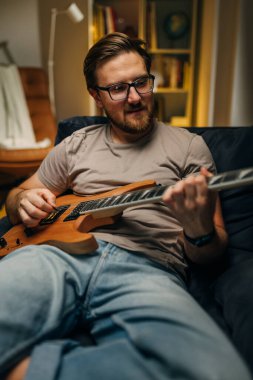 Beyaz, orta yaşlı bir adam gitar çalıyor..