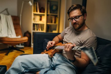 Beyaz adam evde gitar çalıyor..