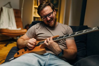 Evinde elektro gitar çalan mutlu bir beyaz adamın ön görüntüsü..