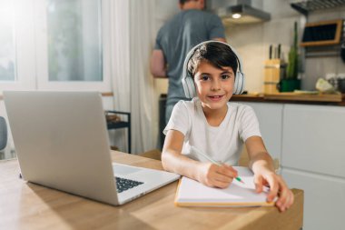 Evden online ders aldığı için mutlu olan beyaz bir çocuğun portresi..