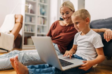 Genç Kafkasyalı annesinin yanında dizüstü bilgisayar kullanıyor..