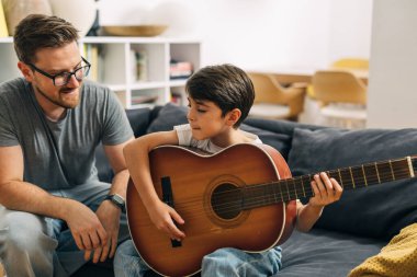 Baba oğluna gitar çalmayı öğretiyor..