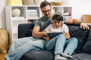 Baba ve oğul oturma odasında dijital tablet kullanıyorlar..