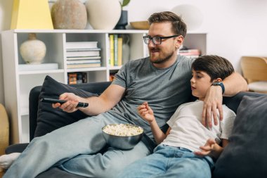 Baba ve oğul evde film izleyip patlamış mısır yerken kaynaşıyorlar..