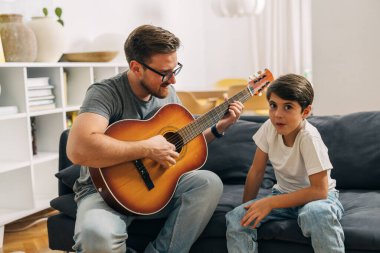 Baba gitarda oğlu için bir şarkı çalıyor..