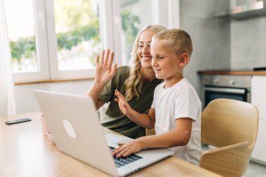 Anne ve oğul internette video görüşmesi yaparken el sallıyorlar..