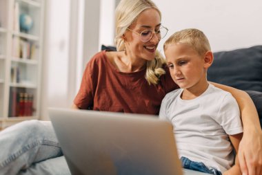 Mutlu anne oğlunun yanında otururken o dizüstü bilgisayar kullanıyor..