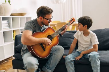 Beyaz adam oğluna gitar çalmayı öğretiyor..