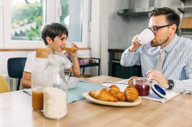 Genç beyaz çocuk babasıyla kahvaltı yapıyor..
