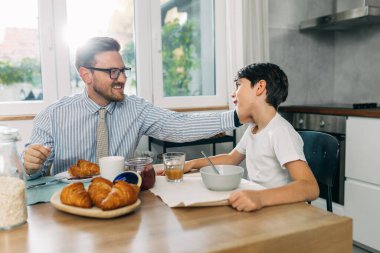 Beyaz bir baba ve oğlu mutfakta kahvaltı yapıyor..