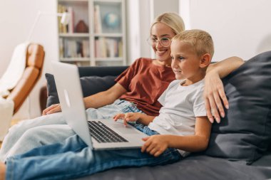 Anne oğlunun dizüstü bilgisayarını kullanmasını izliyor..
