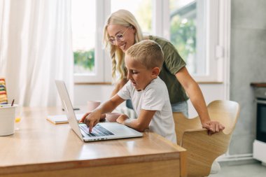 Dizüstü bilgisayar kullanmayı öğrenen şirin bir çocuğun yan görüntüsü..