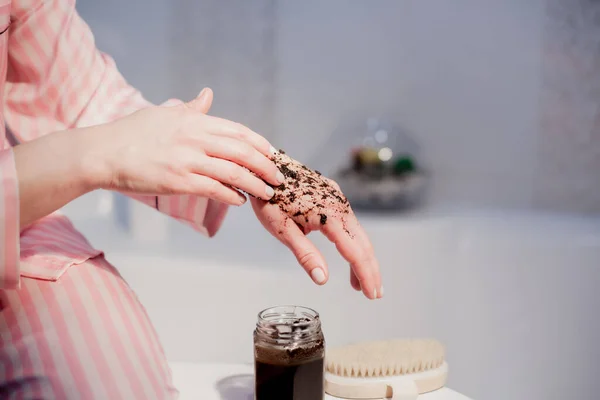 A girl in the bathroom applies a scrub to her hands. Spa procedure at home