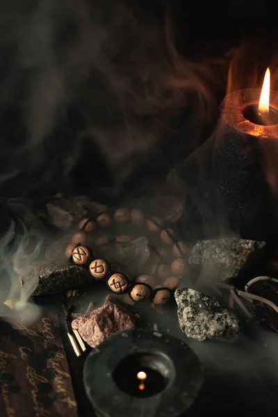 A circle of runic alphabet, a futark, against the background of smoke from a candle lies on a stone. Mystical ritual for divination and prophecy. Selective sharpness on Otal rune