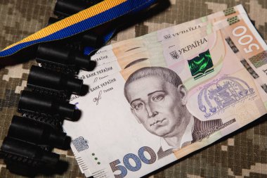 500 Hryvnia banknotuna yakın çekim, makineli tüfek bandı ve askeri piksel üzerinde mavi-sarı. Askeri maaş konsepti. Ukrayna Hryvnia 'sı. Ukrayna 'nın parası.