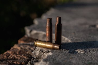Küçük silahlardan çıkan üç mermi bir taşın üzerinde duruyor.